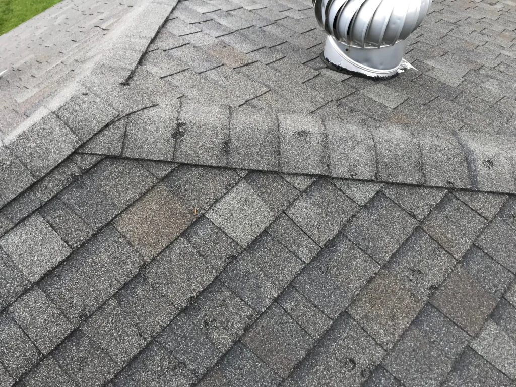 Current image: Roofer inspecting Calgary home for hidden hail impact on shingles