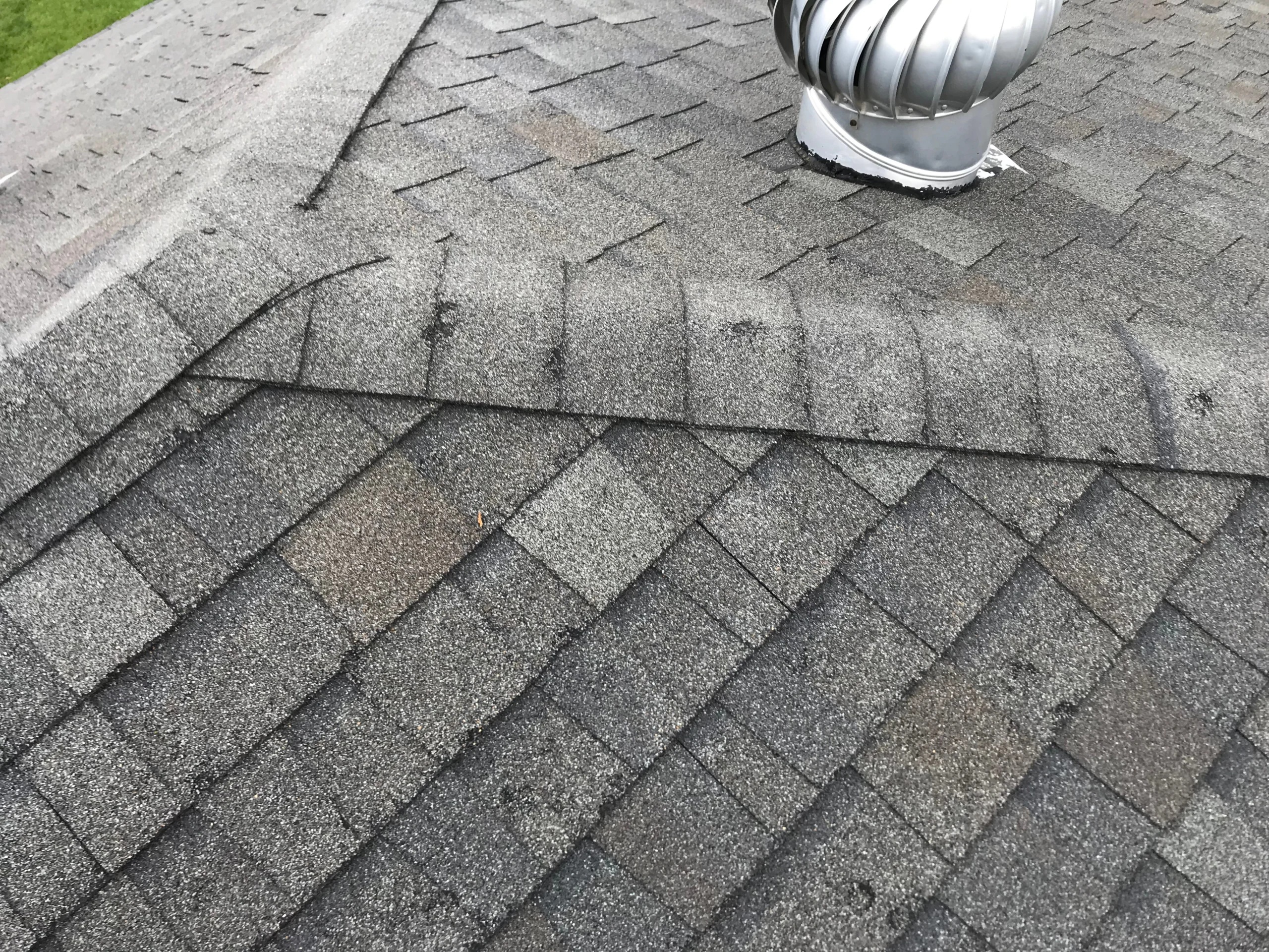 Roofer inspecting Calgary home for hidden hail impact on shingles